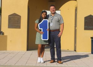 Valedictorian Siya Patel holds a #1 sign indicating her class rank.