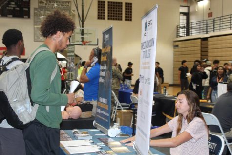 A student converses with a representative from VERTO Education at a career fair table.
