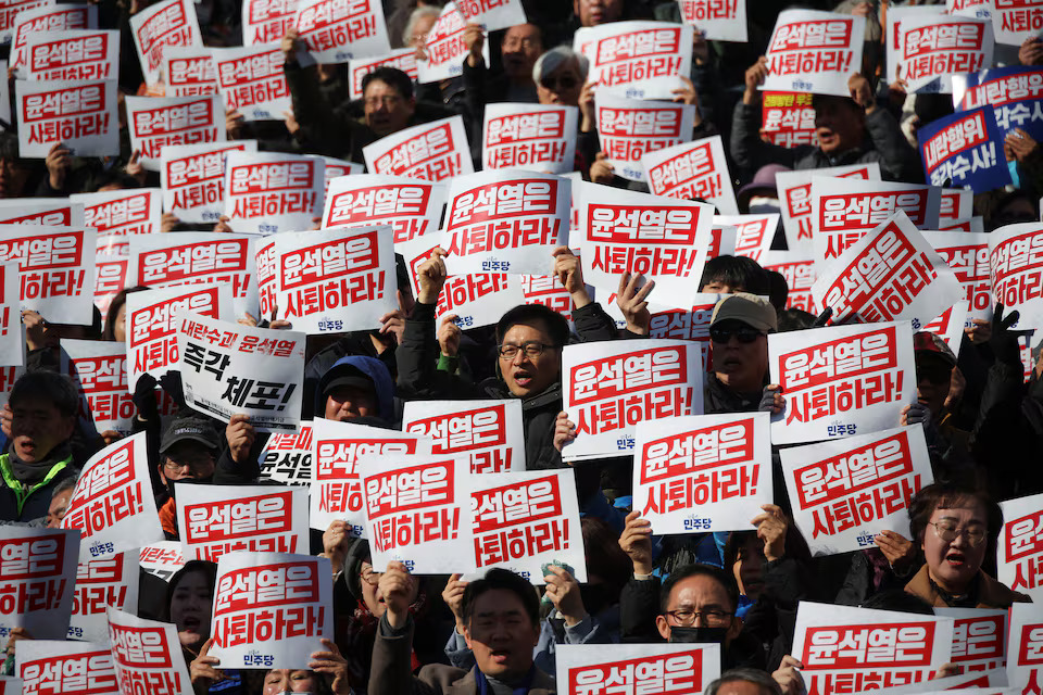 Protesters hold up signs that read "Step down President Yoon Suk Yeol" as people and lawmakers attend a rally in Seoul. Credit: REUTERS/Kim Hong-Ji. 
