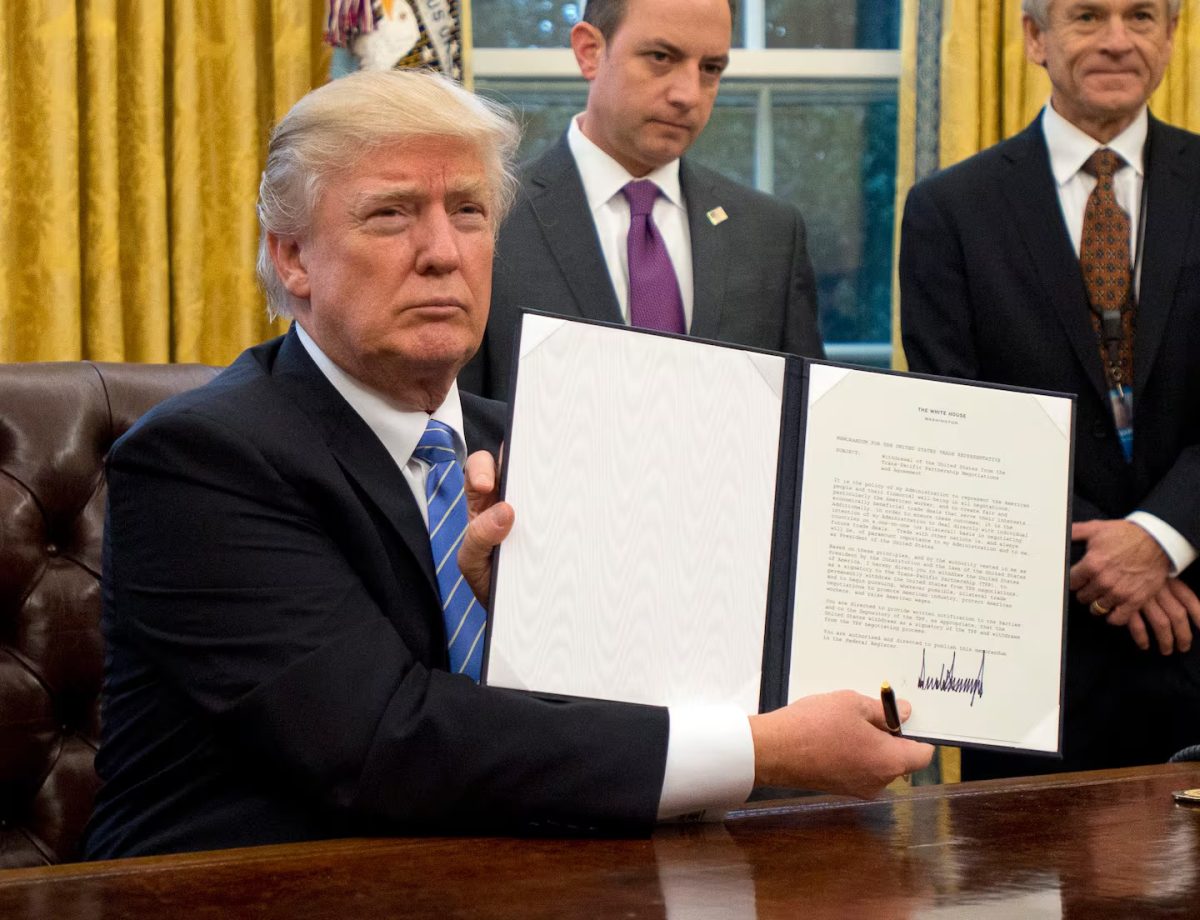 President Donald Trump holds up an executive order he signed in the Oval Office.